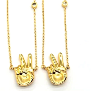Gold plated peace gesture pendant necklace with clear crystal accent on white background