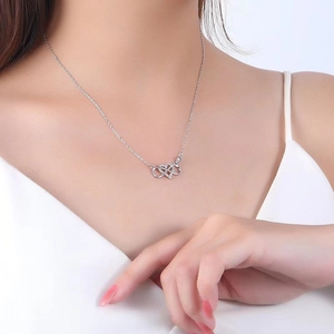Gros plan du collier pendentif cœur infini en argent 925 porté sur le cou d'un modèle