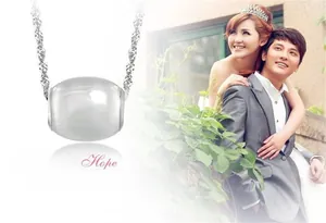 Detailed view of round white cat eye stone pendant with a delicate silver wavy chain