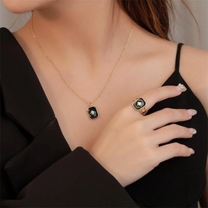 Detail of S925 silver gold-plated necklace and ring set with black enamel star charms