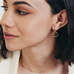 Detail of minimalist S925 heart earrings and beaded necklace on female model