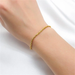Detail of elegant gold rope chain bracelet on wrist with smooth silk background