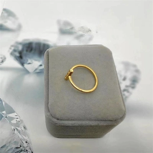 Detailed close-up of a gold-plated T-style open ring on a grey velvet jewelry box