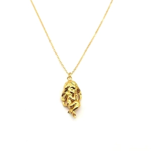 Gros plan d'un pendentif sirène doré stylisé avec détails ciselés sur une chaîne fine
