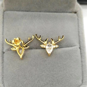 Macro shot of gold reindeer earrings with pear-shaped zircon and sparkling cubic zirconia stones