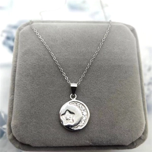Macro detail of S925 silver star and moon pendant with cubic zirconia on velvet