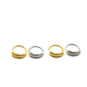 Macro detail of silver and gold feather ear cuffs with intricate carved texture