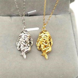 Détail de colliers pendentifs sirène or et argent sur un support en velours gris