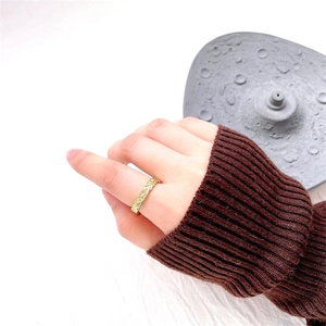 Close-up of a minimalist gold ring with an irregular hammered texture on a model's hand