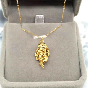 Détail d'un pendentif sirène doré montrant les écailles et la texture des cheveux fins