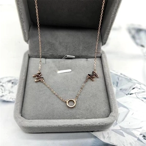 Détail du collier MOM en or rose présenté dans un écrin à bijoux en velours chic