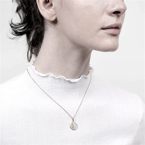 Detail of S925 silver star moon pendant necklace worn on a white knit sweater