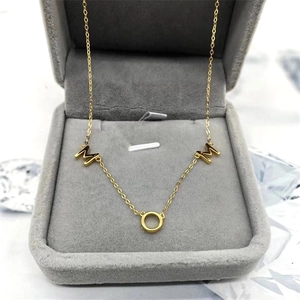 Gros plan du collier avec pendentif MOM doré dans un écrin à bijoux en velours gris