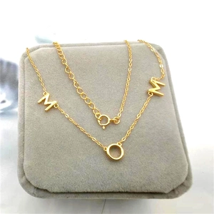 Détail du collier avec pendentif lettre M doré présenté sur un écrin en velours gris