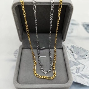 Gros plan de chaînes Figaro or et argent présentées dans un écrin à bijoux en velours