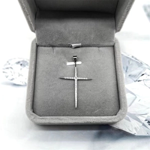 Détail du pendentif croix en argent S925 avec zircons sur un coffret en velours gris