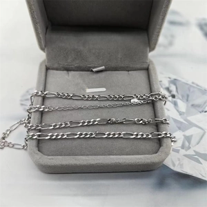 Vue détaillée d'une chaîne Figaro en argent S925 sur un coffret en velours gris