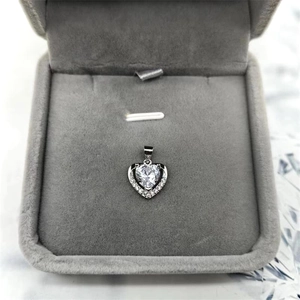 Gros plan du pendentif cœur en argent serti de cristaux sur un fond en velours