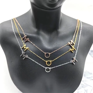 Détail de colliers MOM en or et argent superposés sur un mannequin de mode noir