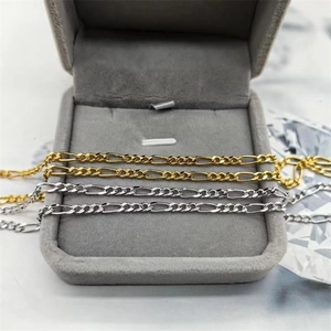 Gros plan de chaînes Figaro en or et argent présentées sur un plateau de bijoux en velours