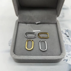 Detailed top view of gold and silver oval hoop earrings in a grey velvet jewelry box