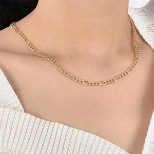 Gros plan d'un collier chaîne Figaro doré classique porté élégamment sur un cou féminin