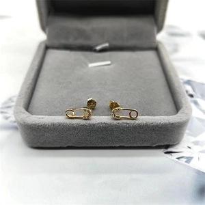 Détail des boucles d'oreilles trombone en argent doré serties de zircones cubiques