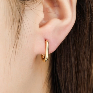 Polished gold U-shaped oval hoop earring on female model showing glossy metallic finish