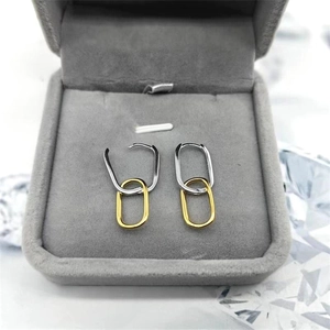Close-up of S925 silver and gold two-tone interlocking chain link earrings in a jewelry box