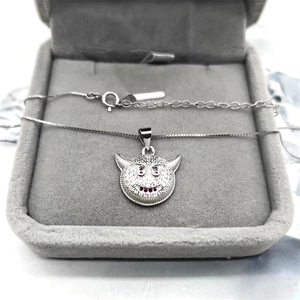Macro shot of silver devil face pendant with purple zircon eyes on gray velvet