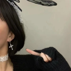 Close-up of S925 silver cross earrings with sparkling zircon on a female model