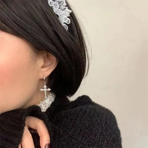 Detail view of S925 silver cross earring with sparkling zircon stones on a female model