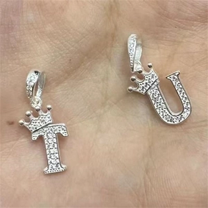Gros plan de pendentifs T et U en argent avec couronnes et zircons cubiques brillants