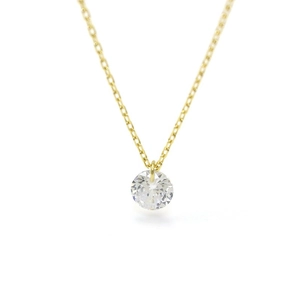 Macro shot of minimalist gold necklace with a brilliant round-cut zircon pendant