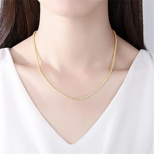 Nahaufnahme einer eleganten Gold-Tennis-Halskette an einem Modell mit V-Ausschnitt-Kleidung