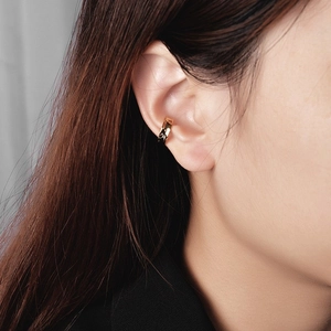 Detail of minimalist hammered gold ear cuff worn on ear cartilage without piercing