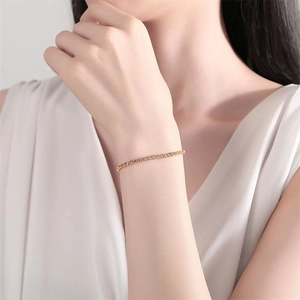 Bracelet rivière ajustable doré 2mm avec zircons élégants porté par une femme chic
