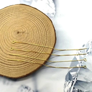 Detailed view of four golden S925 silver box chain earring components on a wood display