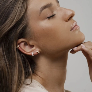 Close-up of sparkling cubic zirconia gold hoop earrings and ear cuff on model ear