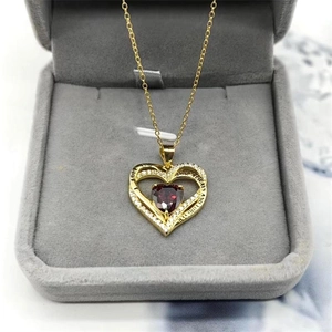 Gros plan du pendentif cœur doré avec pierre rouge et gravure LOVE YOU