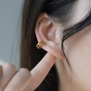 Close-up of golden double-layered cuff earring for non-pierced ears in minimalist style