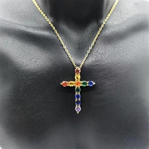 Detailed close-up of a gold cross pendant set with vibrant rainbow-colored gemstones