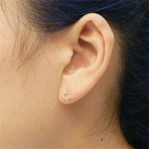 Gros plan d'une puce d'oreille délicate en forme d'étoile à six branches dorée