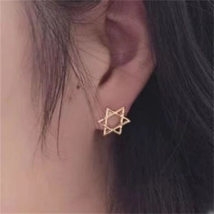 Gros plan de boucles d'oreilles hexagrammes dorées minimalistes sur un mannequin
