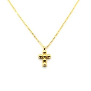 Macro shot of minimalist golden beaded cross pendant on a thin silver link chain