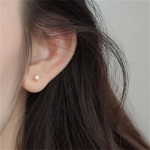 Close-up of minimalist S925 silver four-prong pearl stud earrings worn by a model