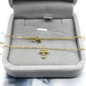 Macro shot of a minimalist gold S925 silver cross pendant necklace on a velvet box