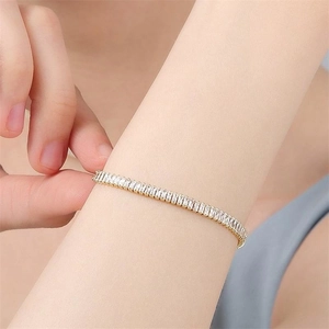 Dettaglio del bracciale tennis dorato con zirconi rettangolari indossato al polso