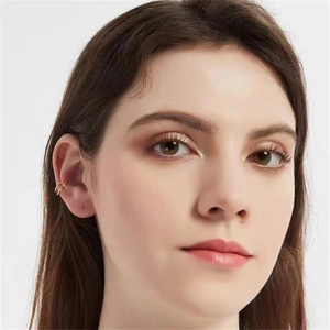 Gros plan d'un ear cuff double couche doré minimaliste porté par un mannequin sur fond blanc