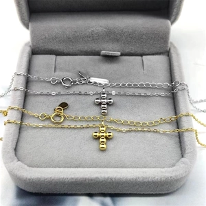 Detail of silver and gold bead cross necklaces on a grey velvet jewelry box display